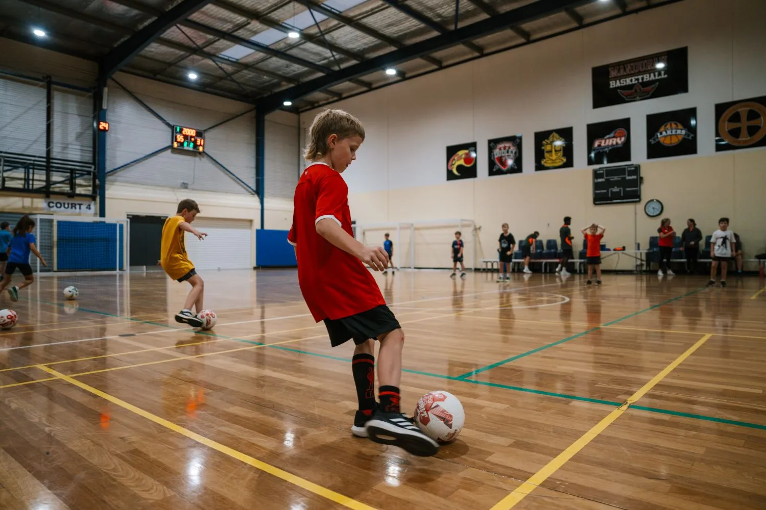 Boy kicking soccer ball on the MARC courts